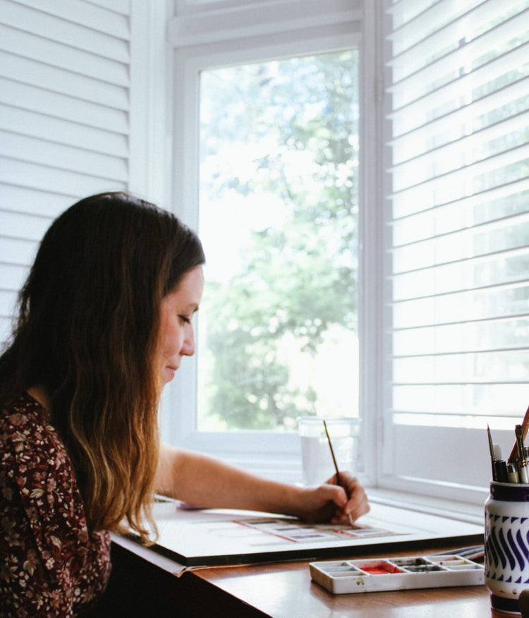 Ana painting a watercolour at her studio window