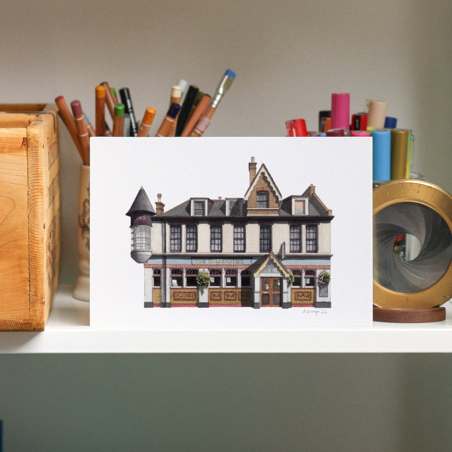 Illustration of a building on a white card with stationery items in the background