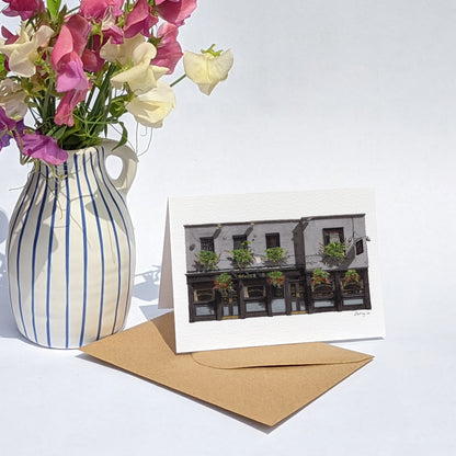 THE SEVEN STARS in Holborn greeting card is paired with a kraft paper envelope and a blue-and-white striped vase filled with pink and white sweet pea flowers.