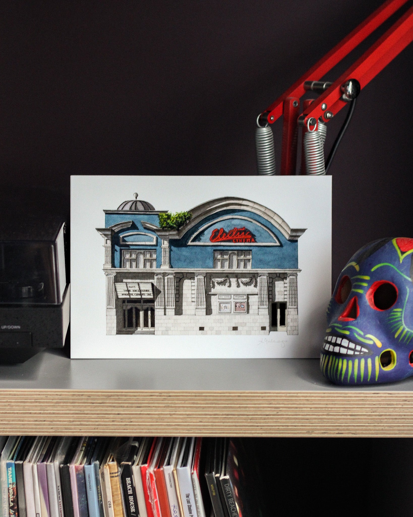 Art print of the Electric Cinema on a shelf next to a colorful skull and records