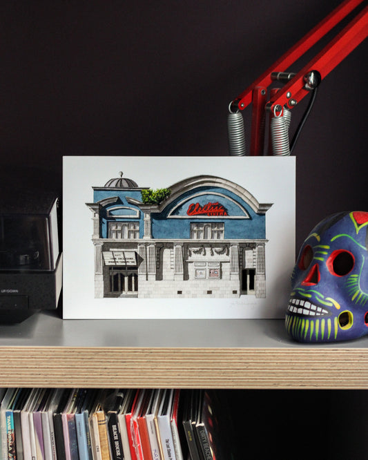 Art print of the Electric Cinema on a shelf next to a colorful skull and records