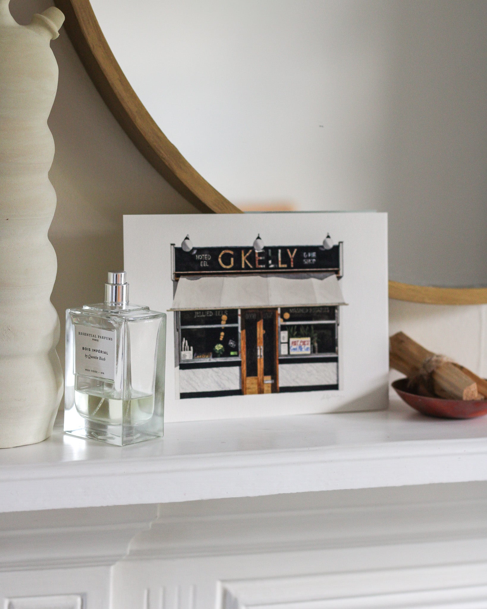 Perfume bottle and unframed picture on a mantelpiece with decorative items.