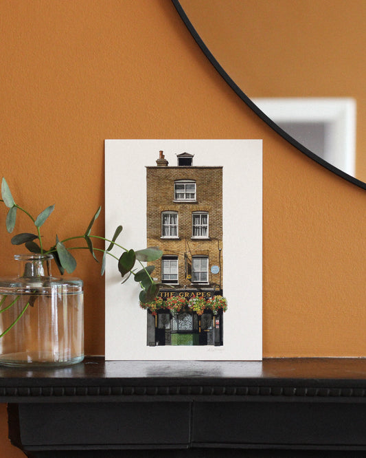 Framed print of The Grapes on an orange wall with a plant and mirror.
